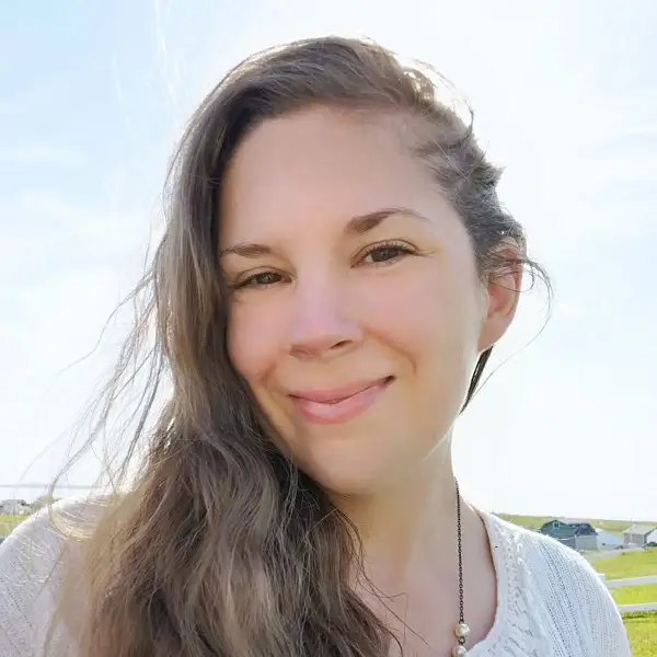 The author photo of a white woman with long brown hair and brown eyes smiling at the camera on a sunny day.